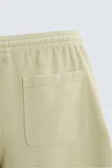 Bermuda de algodón color blanco, de corte relajado (relaxed fit), con cintura elástica ajustable mediante cordón. Posee bolsillos laterales y un bolsillo trasero de plastrón. Presenta un bordado en contraste en la pernera.