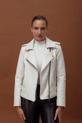 Chaqueta tipo biker de cuero negro con cierre frontal asimétrico, solapas con broches metálicos, bolsillos laterales con cierre y detalles de costuras acolchadas en la parte inferior.