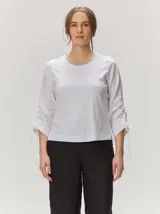 Remera de manga larga color blanco con cuello redondo y detalles fruncidos con lazos en las mangas.