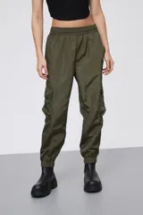 Babucha estilo cargo color verde oliva, confeccionada en tela técnica con acabado satinado. Presenta cintura elástica, bolsillos laterales con solapa y puños elásticos en los tobillos.