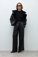 Pantalón de tiro alto confeccionado en eco cuero negro, con diseño de pierna ancha y pinzas frontales.