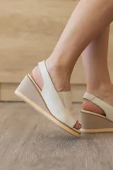 Sandalia de taco corrido confeccionada en 100% cuero vacuno, color beige. Cuenta con capellada envolvente con recorte lateral elástico y tira trasera para mayor sujeción.