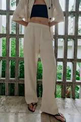 Pantalón de tiro medio confeccionado en lino color beige, de pernera recta con nervios marcados en el delantero. Posee bolsillos frontales, falsos bolsillos de vivo en la espalda y cierre frontal con cremallera, botón interior y gancho.