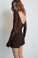 Bermudas de tiro medio color negro, con cintura ancha, bolsillos delanteros y cierre frontal con cremallera y ganchos metálicos.