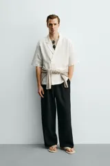 Camisa tipo kimono de corte relaxed fit, color celeste, confeccionada en tejido fluido de viscosa y lino. Presenta cuello con solapas de muesca, manga corta y cierre frontal cruzado con doble botonadura.