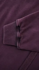 Buzo de cuello alto con efecto de lavado stone wash en color vino. Presenta costuras verticales decorativas en el frente y bordado de la marca en el pecho.