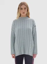 Buzo tejido de algodón con cuello subido, diseño oversized y corte holgado con aberturas laterales en el ruedo. Presenta un patrón de tejido acanalado con detalles de trenzas verticales.