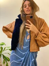 Campera oversize de cuero tostado con solapas y forro interno de corderito sintético azul marino, mangas anchas y detalles de costuras trenzadas.