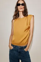 Musculosa de tejido satinado con cuello redondo y detalle de nudo en uno de los hombros.