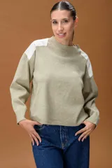 Sweater de punto color beige con cuello redondo y detalles de parches en cuero sintético blanco en los hombros. Presenta mangas largas con puños acanalados y un corte holgado.