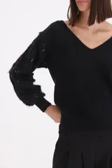Sweater negro de punto con escote en V y mangas largas abullonadas con bordados de lentejuelas al tono.