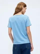 Remera azul de manga corta con cuello redondo y un pequeño oso bordado en el pecho.