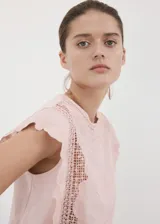 Top de algodón color rosado, con detalles bordados, cuello redondo, mangas cortas y terminaciones festoneadas.
