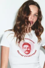 Camiseta blanca de manga corta y cuello redondo, con estampado frontal de Pedro Pascal en un círculo rosado y texto que dice "Mister Fantastic Solves Everything".