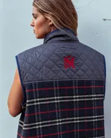 Chaleco con cortes y variantes de tela, con diseño capitoneado en marrón y espalda de tweed a cuadros en tonos rojos y marrones. Cuenta con cuello alto y bolsillos delanteros con cierre.