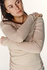 Camiseta de manga larga con diseño asimétrico y efecto de doble capa. Presenta un cuello redondo y un detalle de fruncido lateral que aporta textura a la prenda.