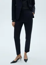 Pantalon de vestir de corte recto y tiro medio, con bolsillos laterales y bolsillos de ribete en la parte posterior. Presenta cierre oculto de botón, gancho y cremallera, y cuenta con trabillas para cinturón.