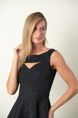 Vestido negro con textura en relieve, falda acampanada y escote con abertura.