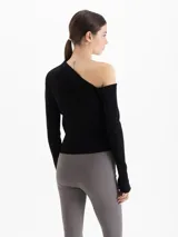 Top de tejido de punto color negro, con diseño al cuerpo, hombros descubiertos y mangas largas.