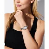 Reloj analógico Michael Kors modelo Suri con caja geométrica de acero inoxidable plateado y pulsera de eslabones tipo cadena. Esfera minimalista en tono plateado con acabado metalizado.