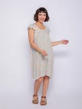 Vestido corto de viscosa con estampado a rayas verticales en tonos celeste, azul y blanco. Sin mangas, con volados en los hombros y escote cuadrado con ribete azul marino.