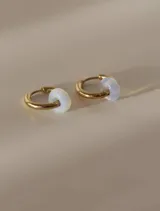 Aros de acero quirúrgico dorados en forma de argolla con dijes de piedra natural negra en forma de dona, desmontables.