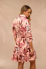 Vestido midi rosado con estampado de flores y hojas en tonos marrones y fucsias, de corte camisero con cuello tipo solapa, mangas tres cuartos, cierre frontal con botones y lazo ajustable en la cintura.