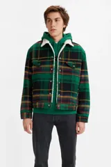 Campera tipo trucker con estampado a cuadros en tonos verdes, negros y amarillos. Presenta cuello y forro interior de corderito (sherpa) blanco, cierre frontal con botones metálicos y bolsillos en el pecho con solapa.