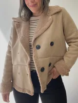 Chaqueta negra con forro tipo corderito, doble botonadura y cuello solapa.