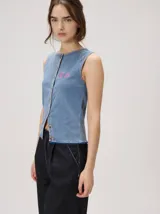 Musculosa de punto gris con efecto lavado, silueta recta, cierre frontal con botones y terminación festoneada en el ruedo y las sisas. Cuenta con un pequeño bordado en el pecho.