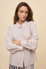 Camisa de manga larga color celeste, con cuello clásico y botonadura frontal. Presenta un calce relajado, con mangas amplias y puños anchos.