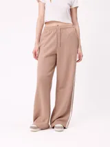 Pantalon de jogging de corte ancho, color beige, con cintura elástica ajustable mediante cordón y franjas laterales blancas.