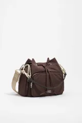 Bolso bandolera de nailon marrón de Bimba y Lola, con cierre de cordón ajustable, bolsillo frontal con cremallera y el logotipo de la marca impreso. Cuenta con una correa ajustable ancha de lona beige y detalles de cuerdas decorativas en los laterales.