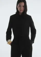 Chaqueta corta de diseño recto, confeccionada en tejido mezcla de lana. Presenta cuello de solapa, cierre frontal de botones y dos bolsillos laterales de ribete. Incluye forro interior y mangas largas.