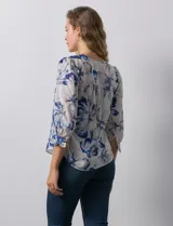 Blusa de gasa estampada con flores azules y blancas, marca Sioni. Tiene escote en V, abertura frontal con botones y mangas 3/4 con puños fruncidos y botón.