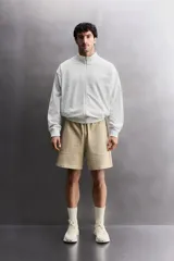 Sudadera de corte relajado con cierre frontal de cremallera, confeccionada en tejido ligero de mezcla de algodón. Presenta cuello subido, manga larga, bolsillos laterales ocultos en costura y acabados en rib.