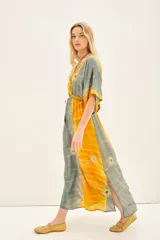 Vestido midi de estilo boho, confeccionado en viscosa con paneles alternados en colores amarillo y verde grisáceo. Presenta un estampado floral con detalles bordados en hilo de lurex, escote en V profundo, mangas anchas al codo y ajuste elástico en la cintura.
