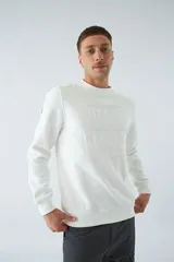 Buzo blanco de felpa con cuello redondo, mangas largas y puños. Presenta un estampado en relieve con texto y logo en goma.