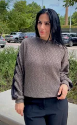 Blusa de tejido de punto en color gris, con cuello redondo y mangas largas que presentan un detalle de encaje negro a lo largo de los brazos.