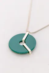 Collar plateado con dije circular de color verde esmeralda y apliques plateados.