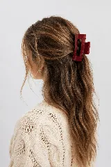 Pinza de pelo bordó de diseño rectangular con abertura central, ideal para recoger el cabello.