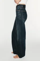 Jeans de tiro alto y estilo wide leg, con diseño de cinco bolsillos, lavado oscuro con efecto desgastado, pierna ancha larga y bajo sin costuras.