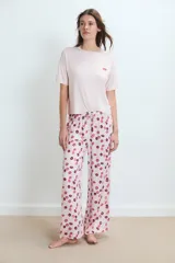 Pijama compuesto por una remera de manga corta en color rosa claro con un pequeño bordado de labios en el pecho y un pantalón largo estampado con motivos de labios en tonos rojos y rosas.