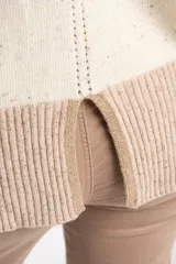 Sweater oversize de lana con diseño color block, combinando un cuerpo en tono crema con motas multicolores y una franja inferior ancha en color visón. Presenta cuello redondo y detalles acanalados en el cuello, puños y ruedo, además de franjas laterales texturizadas en las mangas.
