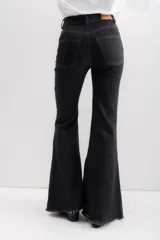 Jean de corte acampanado con cintura alta, confeccionado en denim azul oscuro. Presenta costuras en contraste y un acabado deshilachado en el ruedo.