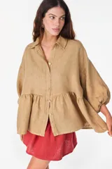 Camisa de lino marrón oscuro con silueta holgada, cuello camisero, cierre frontal de botones claros, mangas voluminosas y detalle de frunces en la cintura.