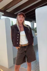 Chaleco vintage de jean color marrón oscuro, con cuello solapa, cierre frontal con botones metálicos, bolsillos delanteros con solapa y corte oversize.