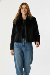 Chaqueta corta de piel sintética en color negro, con cuello clásico, cierre frontal con cremallera y mangas largas.