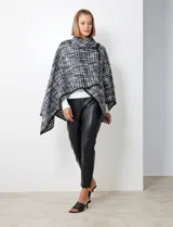 Capa de tejido tweed en blanco y negro, con cuello alto y cierre cruzado con botón de trenca.