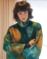 Tapado de lana merino afieltrada con teñido artesanal tie dye en tonos verdes y ocres. Tiene cuello alto, cierre cruzado asimétrico con broches, bolsillos laterales y corte holgado.